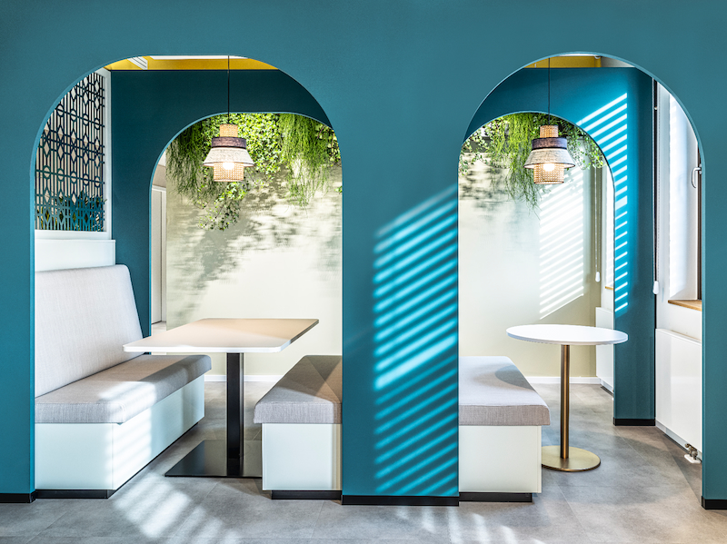 Gezellige zitnissen bij JetBrains München met hangende groene beplanting en zachte indirecte verlichting, ontworpen door MOSS.