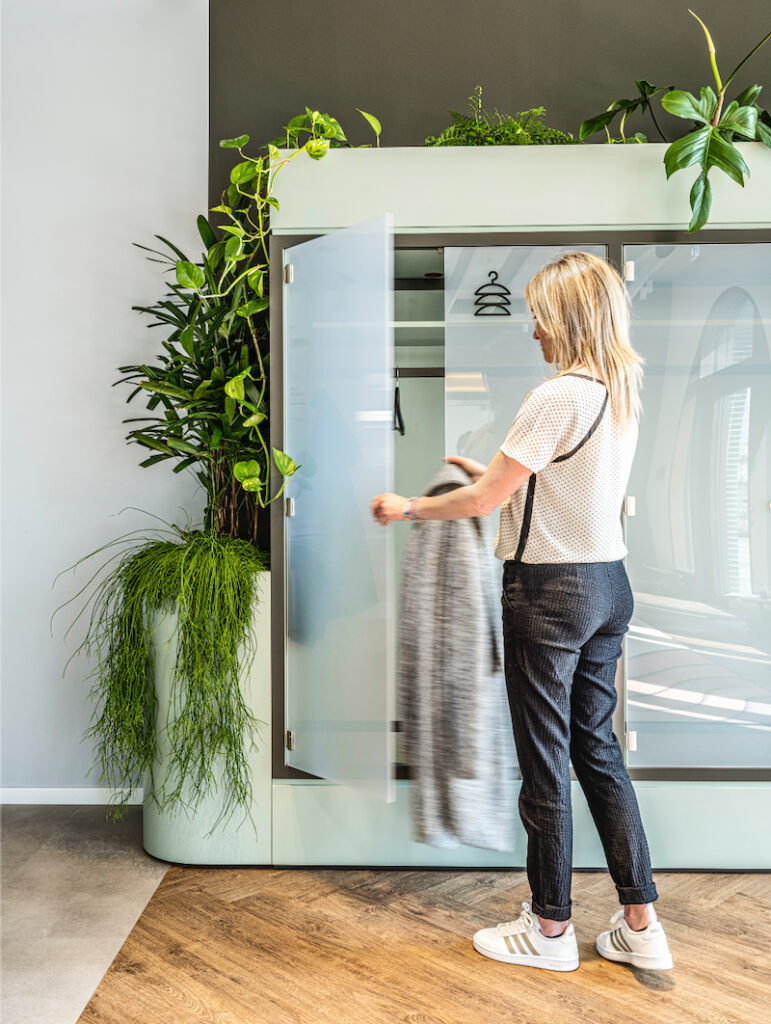 Medewerker gebruikt een garderobekast in het JetBrains-kantoor in München, omringd door geïntegreerde interieurbeplanting die de ruimte een frisse, natuurlijke uitstraling geeft.