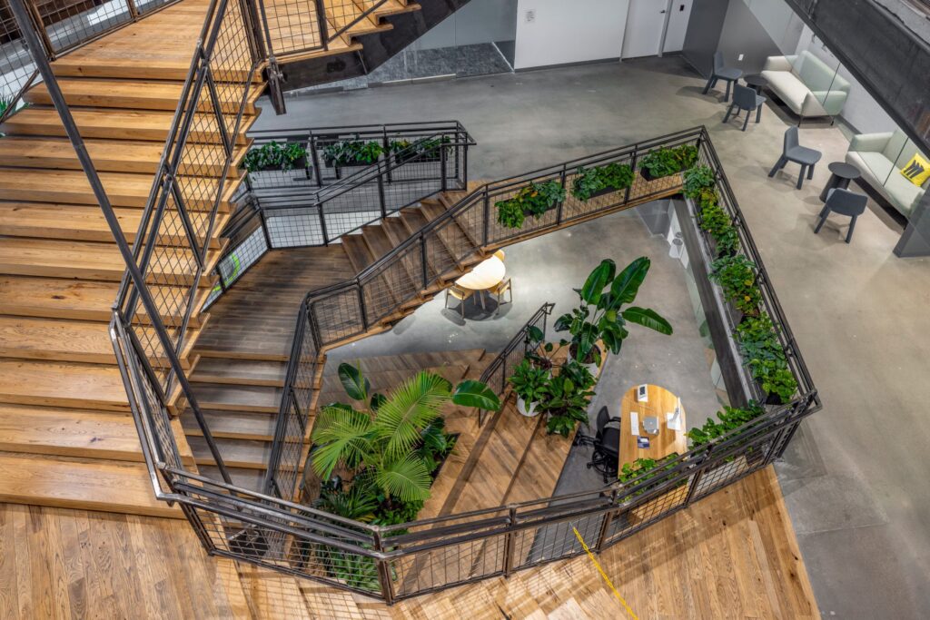 Overzicht van de centrale trapzone in het Miro-kantoor in Austin, met meerlaagse beplanting langs de balustrades en grote tropische planten in het atrium.