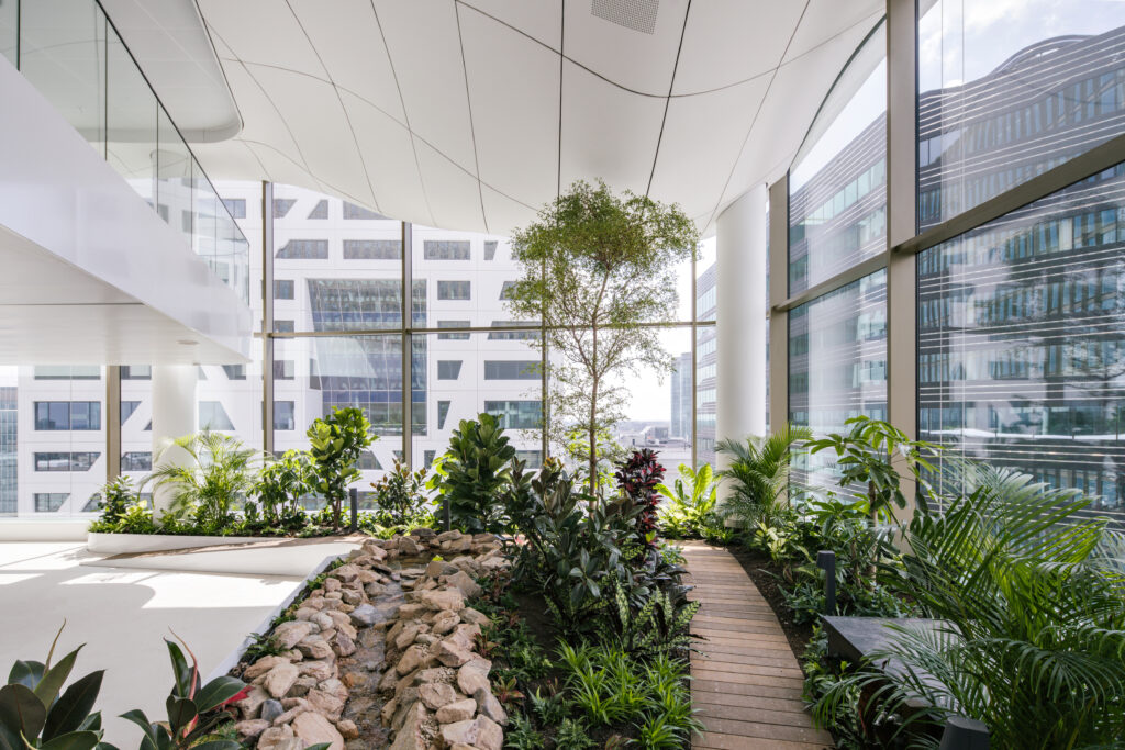 Multi-level indoor park with integrated seating and trees inside Central Park Utrecht high-rise office building