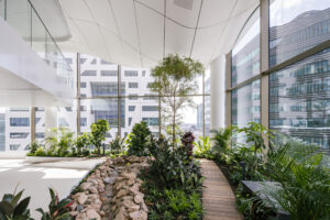 Multi-level indoor park with integrated seating and trees inside Central Park Utrecht high-rise office building
