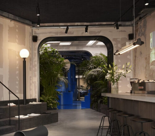 Doorgang met weelderige kamerplanten die de lounge verbinden met de blauwe centrale ruimte in de Lynk & Co Club Berlin, ontworpen door MOSS.