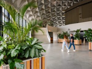 Groene lobby van Circa Amsterdam met grote plantenbakken en trap, ontworpen door MOSS