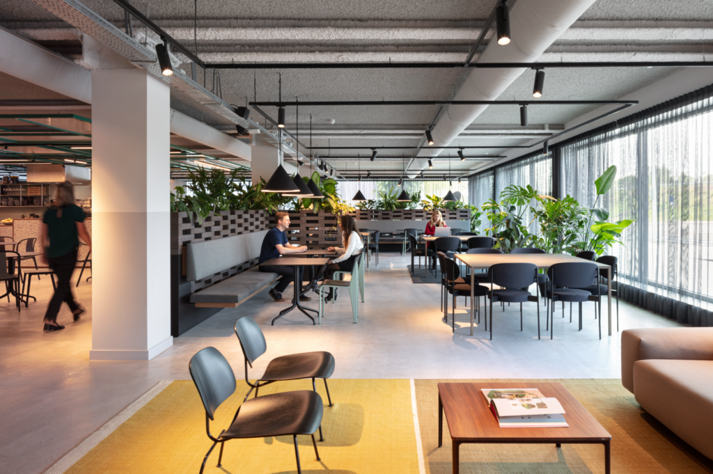 Collaborative office lounge at The Core Amsterdam featuring indoor plants, natural daylight, and flexible seating areas surrounded by greenery.