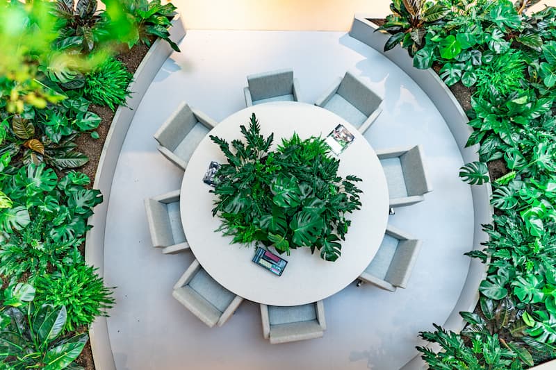 Circular meeting area at elho Tilburg featuring a central planter filled with lush greenery as part of a biophilic office design.
