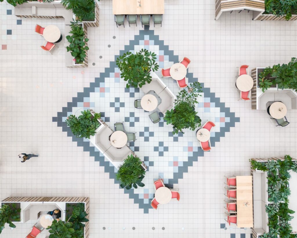 Overhead view of the Dr. Sarphatihuis atrium in Amsterdam featuring integrated indoor planting, modular seating, and biophilic design for elderly care and social well-being.
