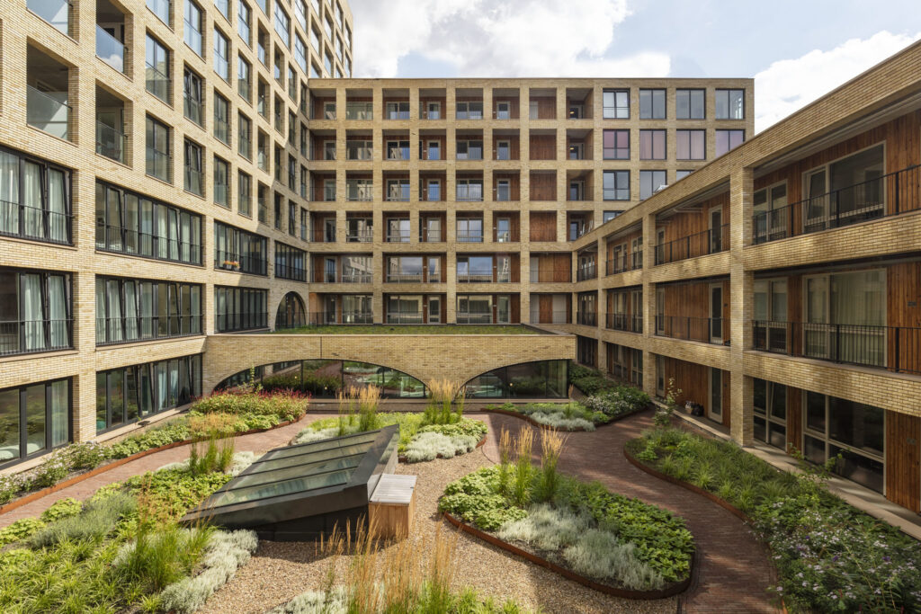 Groene binnentuin in wooncomplex Westbeat Amsterdam met natuurlijke beplanting, slingerende paden en duurzaam ontworpen binnenhof