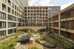 Groene binnentuin in wooncomplex Westbeat Amsterdam met natuurlijke beplanting, slingerende paden en duurzaam ontworpen binnenhof