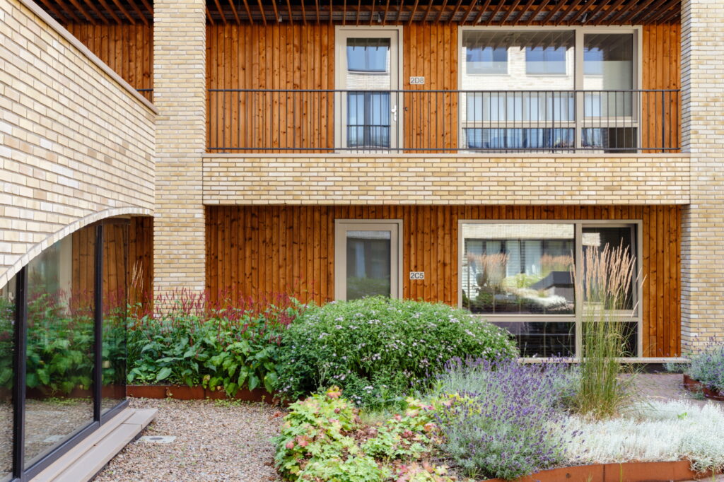 Gevel en binnentuin van wooncomplex Westbeat Amsterdam met duurzame beplanting, houten gevels en groene binnenhof