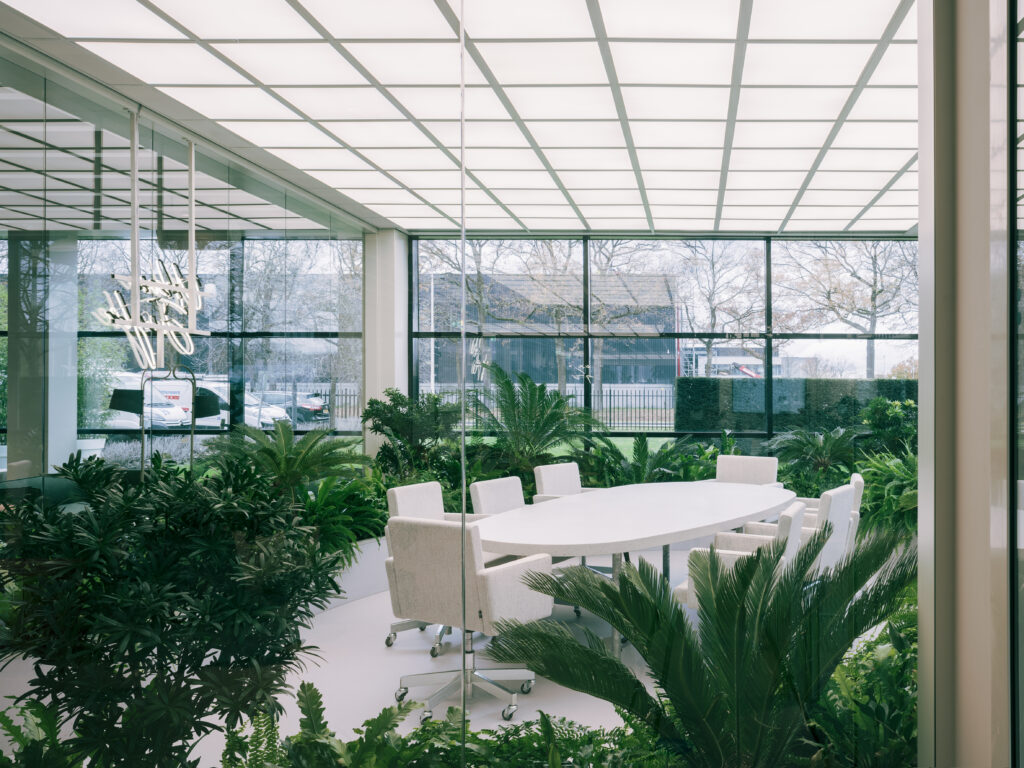 Contemporary meeting area surrounded by tropical indoor planting and large architectural foliage at Elho headquarters in Tilburg, designed by MOSS.