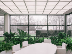 Meeting room overlooking lush indoor gardens with tropical plants and large windows at Elho headquarters in Tilburg, designed by MOSS.