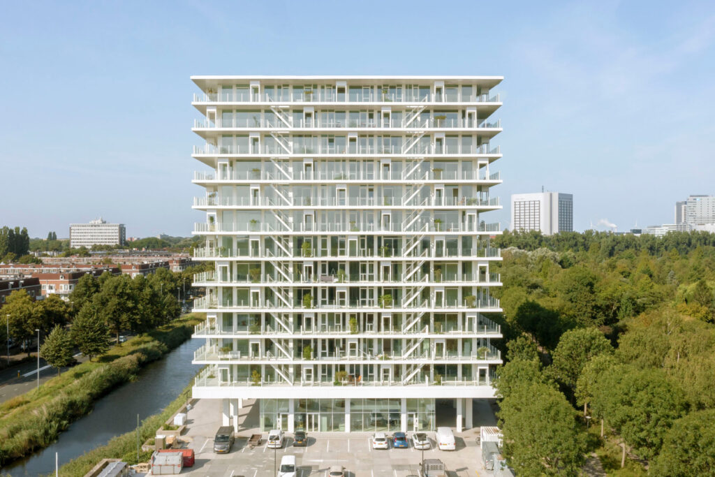 Residential building in Amsterdam with layered balconies and integrated greenery along a canal