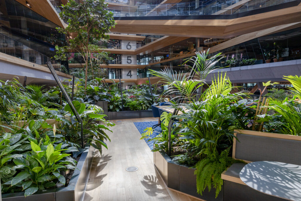 Indoor garden workspace with tropical planting in Booking.com Amsterdam atrium biophilic office design