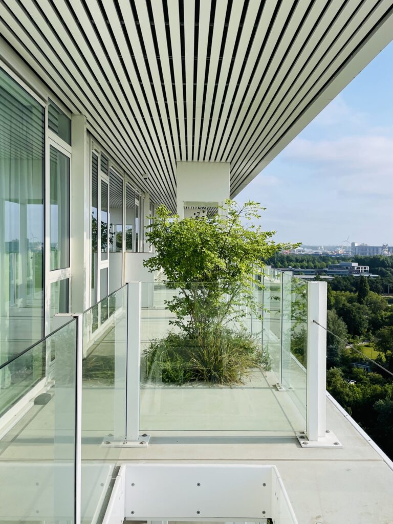 Planted residential balcony at Voortuinen Amsterdam featuring integrated greenery, glass balustrades, and views over the Amsterdam landscape.