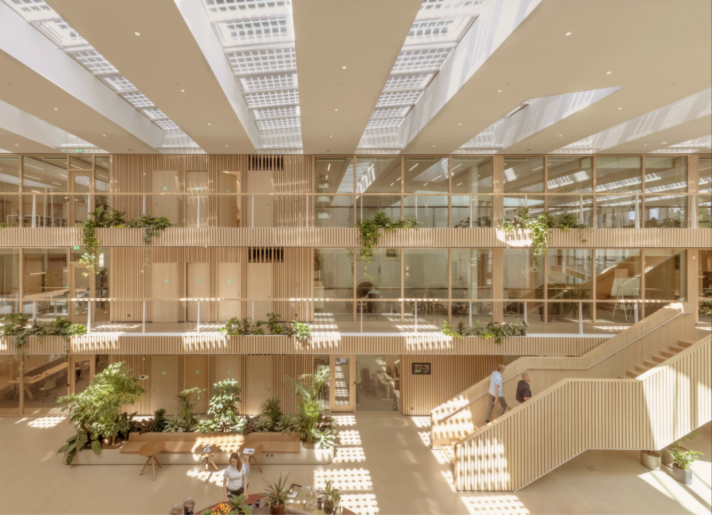 Multi-level atrium with integrated greenery at DSM-Firmenich Maastricht showing biophilic office design, open staircases, and daylight-filled interior architecture