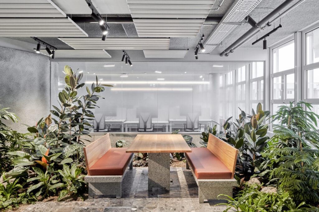Biophilic meeting space at Holcim Switzerland featuring integrated tropical planting, natural materials, and collaborative seating designed by MOSS.