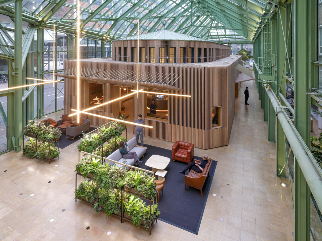 Biophilic atrium at Rijkskantoor B73 with indoor planting, seating, and wooden pavilion