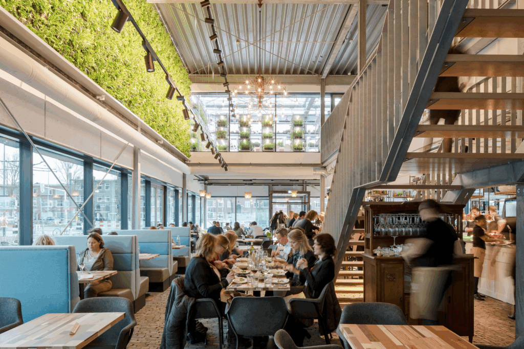 Restaurant interior at The Green House Utrecht featuring a living green wall, urban greenhouse cultivation, and biophilic design integrated into a circular hospitality concept.