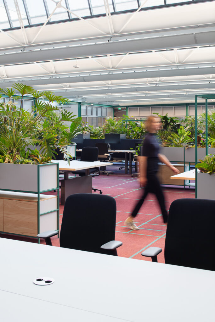 Open-plan office at The Core Amsterdam featuring integrated planters, tropical greenery, and flexible workstations designed by MOSS.