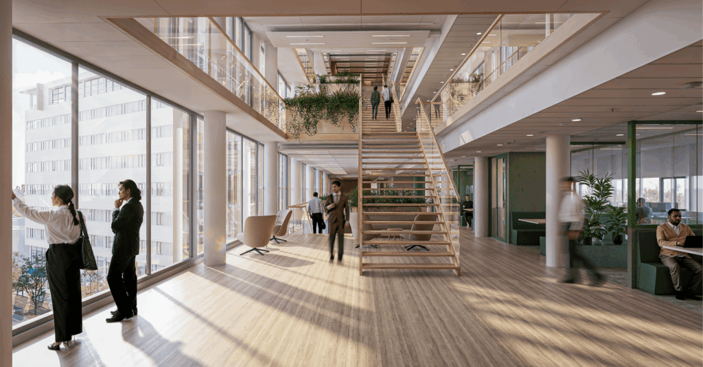Biophilic office atrium at Haagse Veste featuring natural materials, integrated greenery, and collaborative workspaces connected by a central staircase.