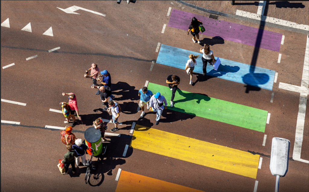 Pedestrians crossing colorful urban crosswalk illustrating inclusive city design, walkability, and human-centered public space
