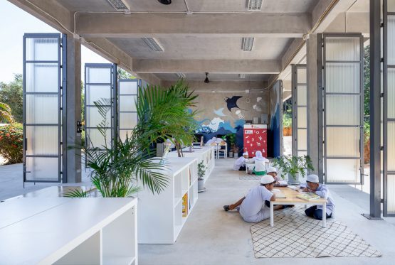 Children learning in open classroom with natural light and indoor plants