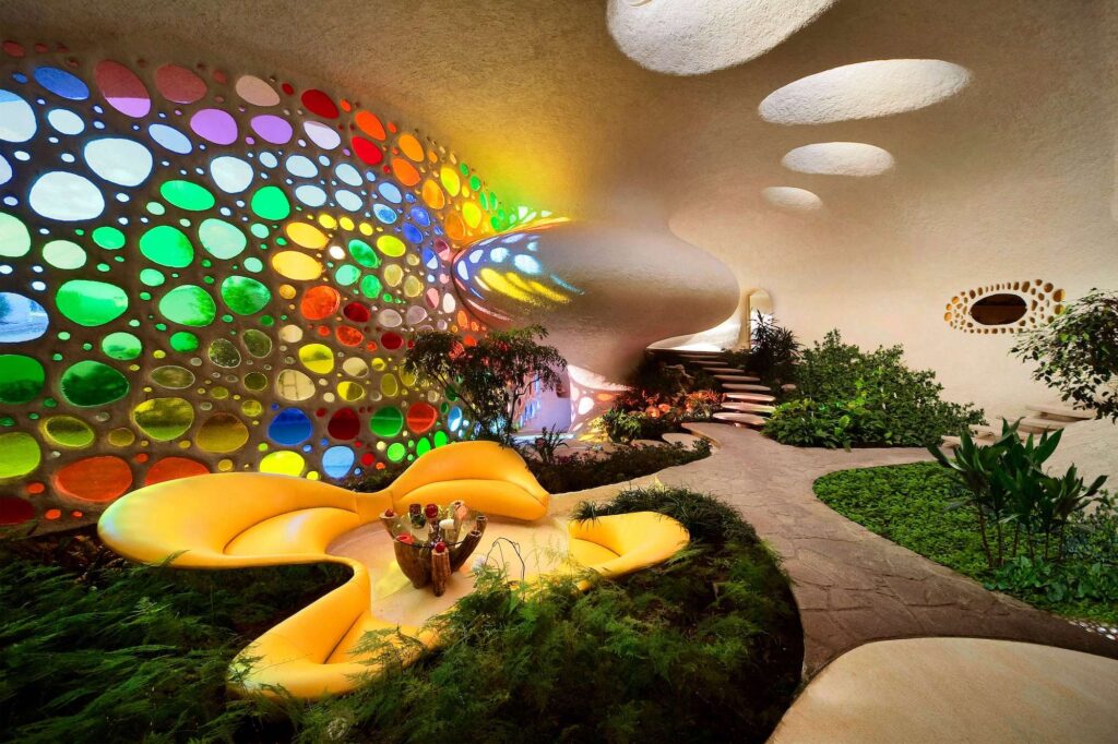 Organic interior architecture with colorful stained glass wall, flowing forms, and indoor greenery in Nautilus House by Javier Senosiain