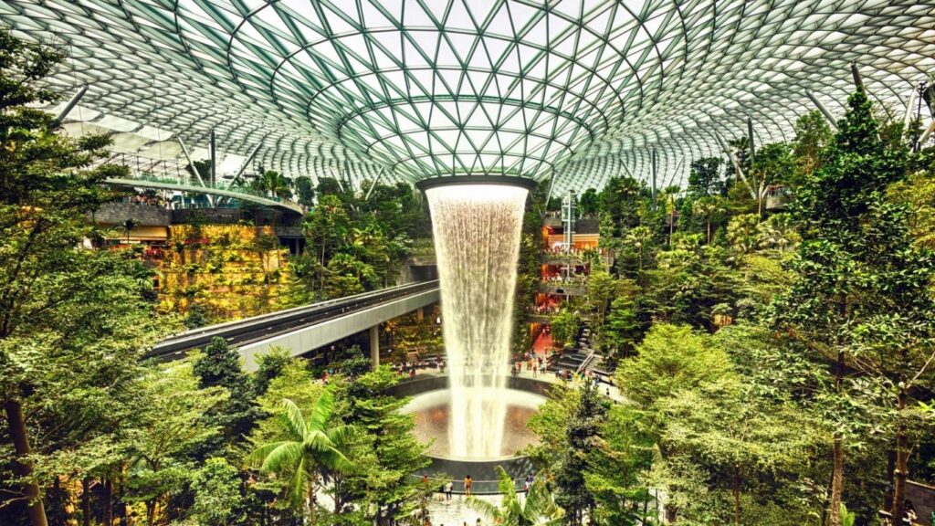 Indoor rainforest with waterfall at Jewel Changi Airport showcasing large-scale biophilic architecture and urban nature integration