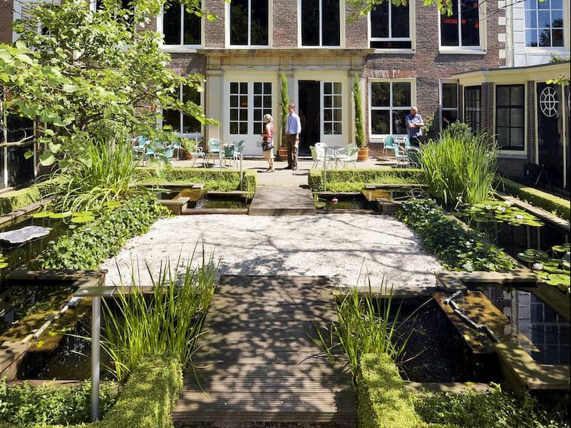 Urban courtyard garden in Amsterdam with integrated water features, natural planting, and biophilic landscape design