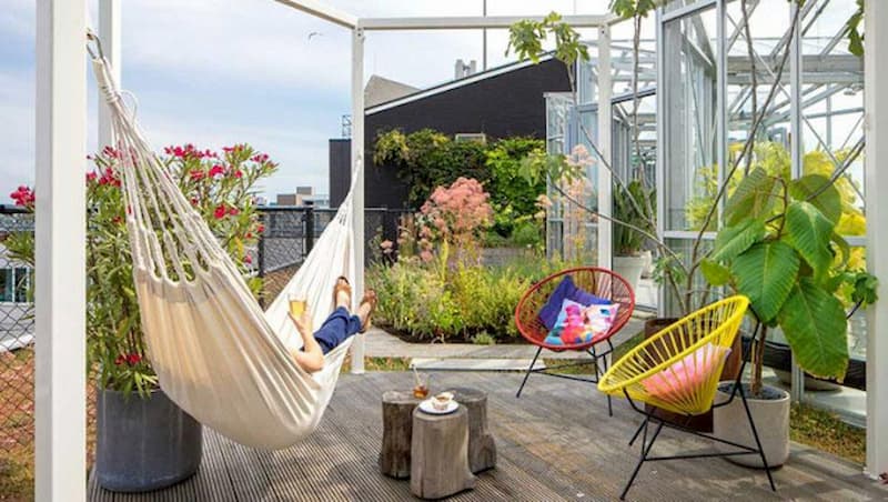 Rooftop garden at Zoku Amsterdam with hammock, lush planting, and biophilic design creating a relaxing urban green space