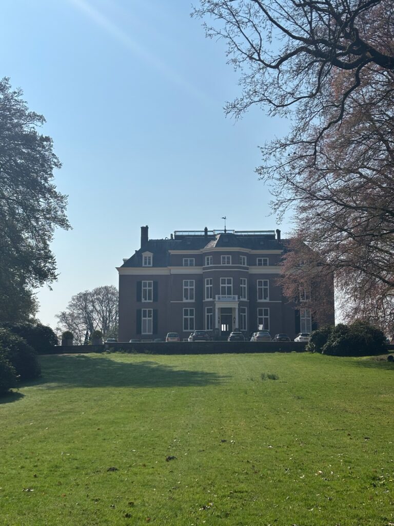 Historic estate building surrounded by open lawn and mature trees, illustrating integration of architecture and landscape design